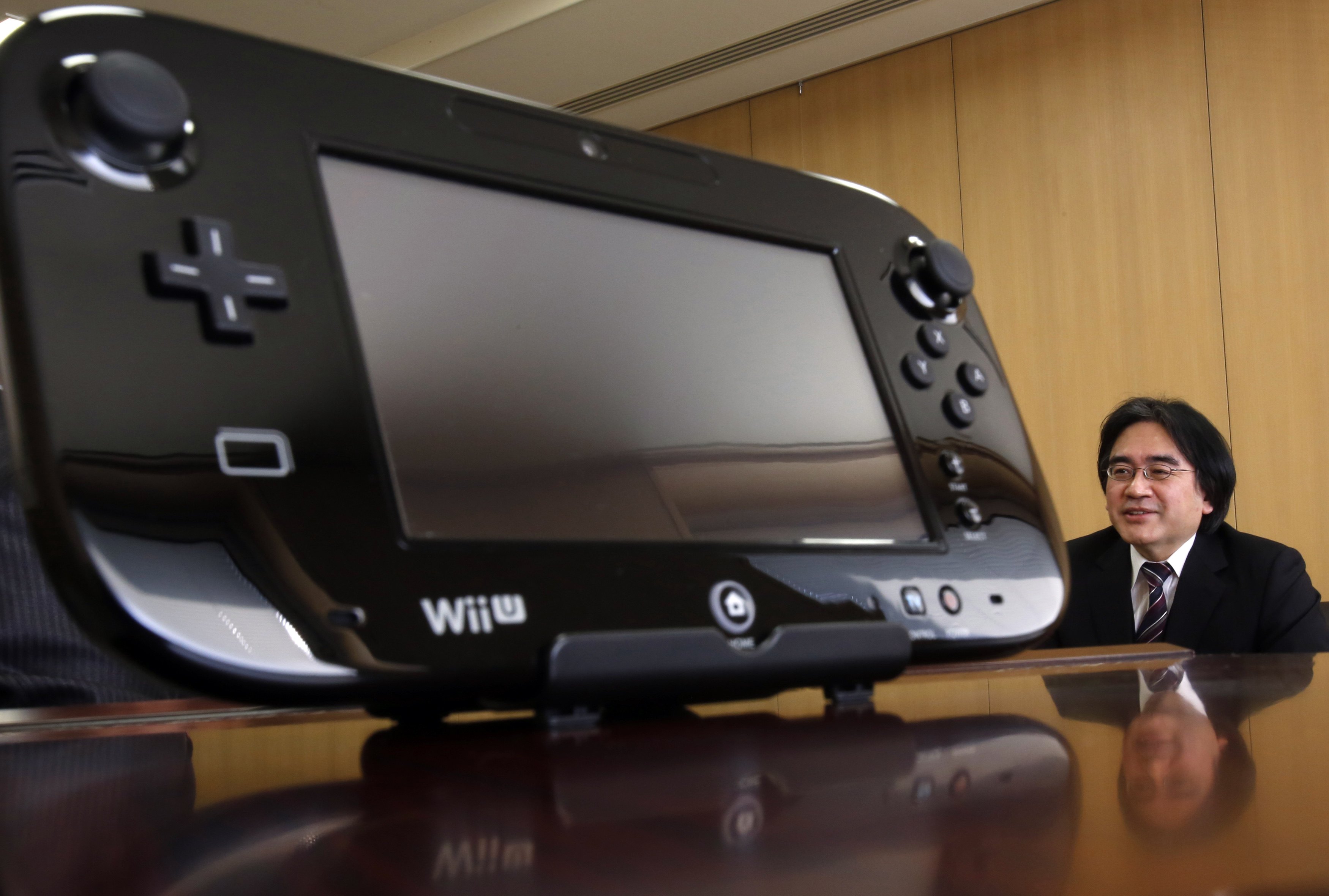 Nintendo Co's President Satoru Iwata speaks next to company's Wii U game controller during an interview with Reuters at the company headquarters in Kyoto, western Japan